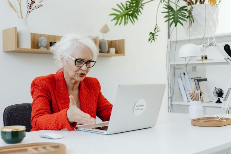 Professional mature businessperson working confidently on laptop with AI interface graphics, modern bright office setting, natural lighting, corporate atmosphere, showing expertise and determination, stock photo style, pexels keyword: mature professional technology — Formations 90
