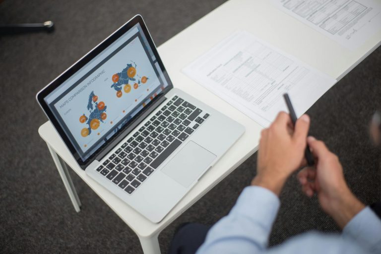 Professional training scene with person working on laptop in modern office environment, financial documents and CPF certification papers visible on desk, bright natural lighting, contemporary workspace atmosphere, stock photo style, keyword: professional training office — Formations 90